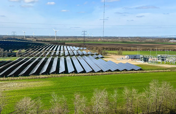 Solar panels and wind turbines in a green landscape, European Energy logo visible.