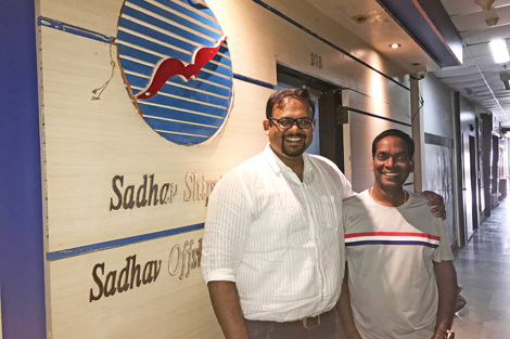 两人在 Sadhav Shipping 办公室标志前微笑。